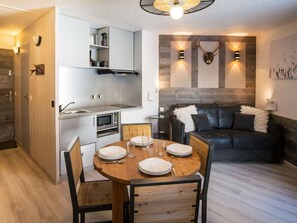 Un espacio habitable pequeño con kitchenette, comedor y una zona de estar acogedora.