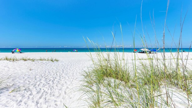 A beach with white sand, clear blue sky, and a few umbrellas. - Paradise Palms-private Beach Access-heated Pool-water Views From Every Room (Bradenton Beach)