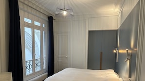 Ein Schlafzimmer mit einem großen Bett, einem Kleiderschrank, einem Heizkörper und einem Fenster mit Vorhängen.