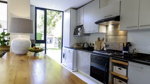 A modern kitchen with white cabinets, a built-in oven, and a large window.