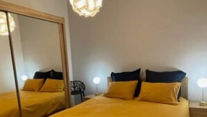A bedroom with a large bed, a mirror, and a hanging light fixture. - Vieux-nice 3 Pièces Confortable et Calme (Nice)