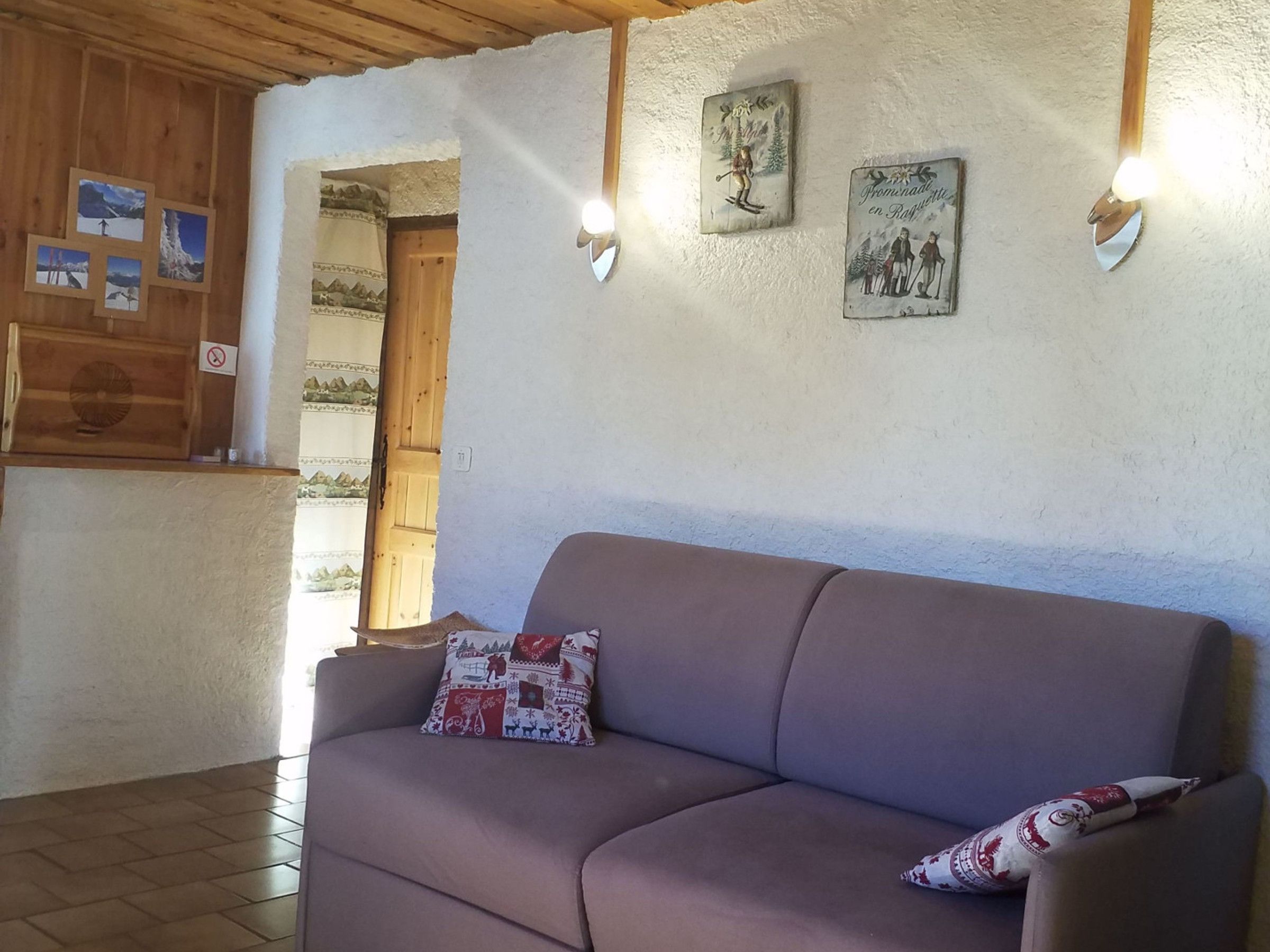 Quarto com sofá, porta de madeira e luminárias fixadas na parede.