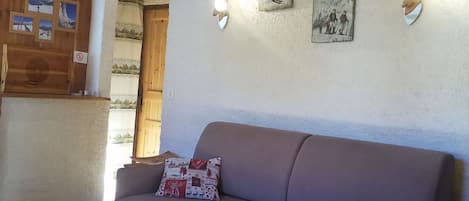 Quarto com sofá, porta de madeira e luminárias fixadas na parede.