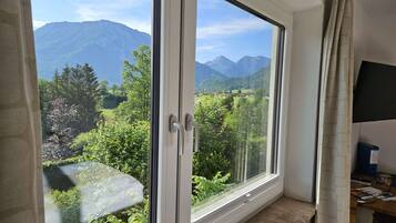 Ein Zimmer mit großem Fenster und Blick auf Berge und grüne Landschaft.