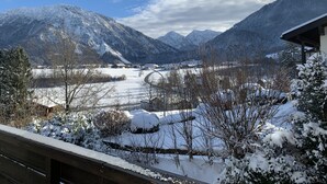 A snowy mountain landscape with a clear sky, a frozen lake, and a building with a sloped roof.