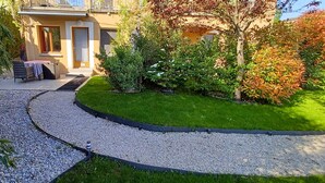 Um caminho no jardim leva a um edifício com porta e janelas.