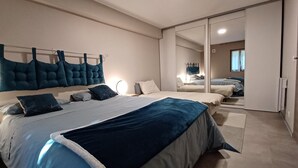 Quarto com cama, mesas de cabeceira, guarda-roupa e espelho.
