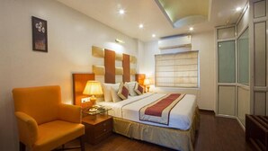 Une chambre d’hôtel avec un lit, une table de chevet, une chaise et une fenêtre avec des stores.