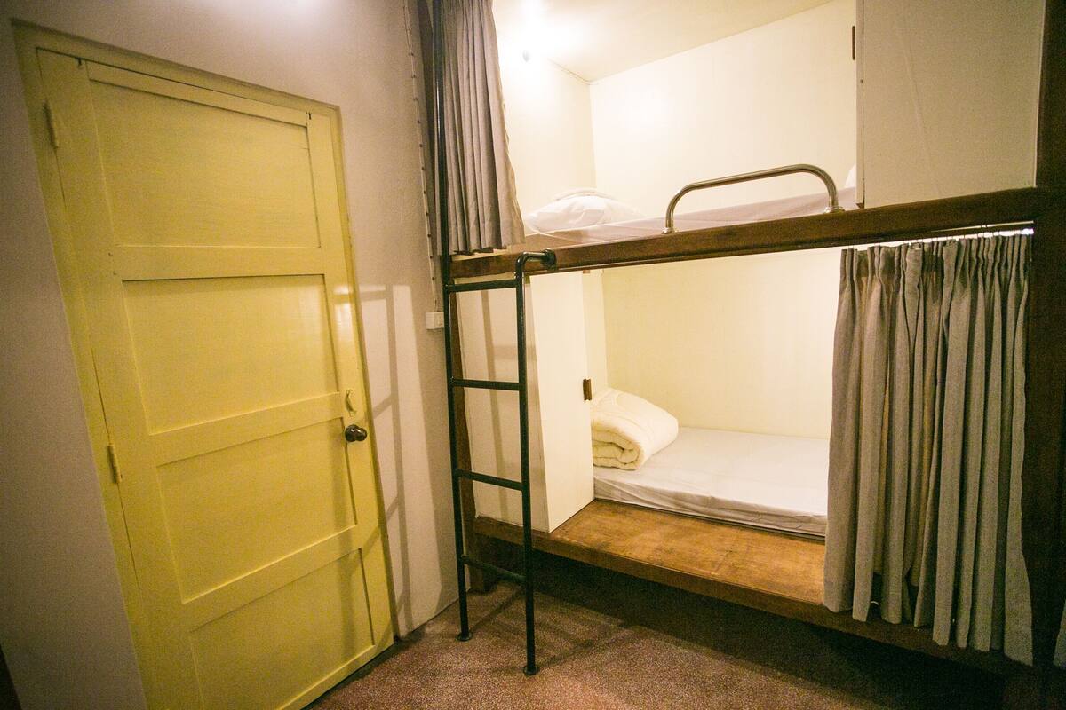 A single bunk bed room with a door and curtains.