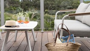 A wooden deck with a white table, a wicker basket, and a white sofa.