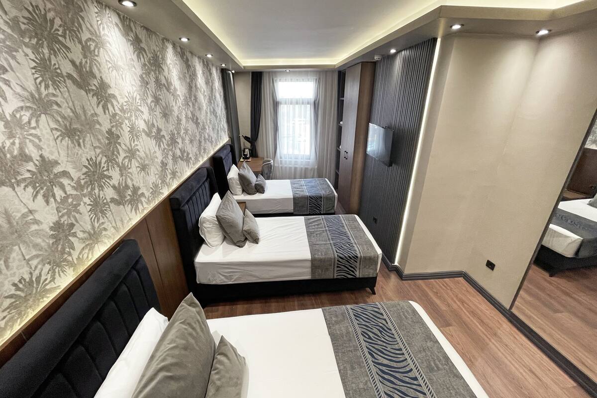 A hotel room with two beds, a TV, and a view of the city.