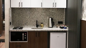 Una cocina compacta con armarios blancos, encimera de granito, lavavajillas integrado y cafetera.