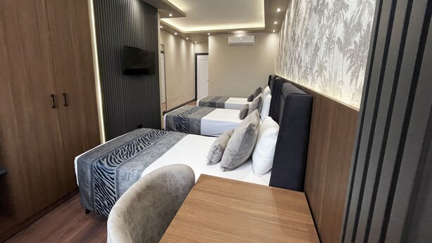 Ein modernes Hotelzimmer mit zwei Betten, einem Holztisch und einem Fernseher.