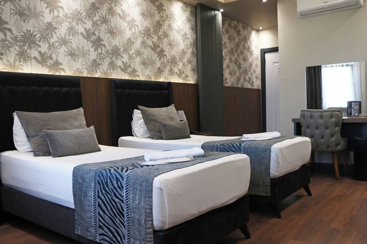 A hotel room with two beds, a desk, and a chair.