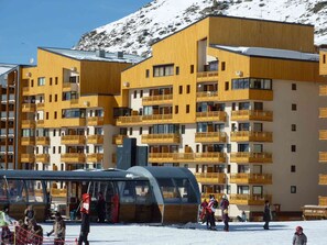 Hotel de vários andares com varandas e um teleférico ao fundo.