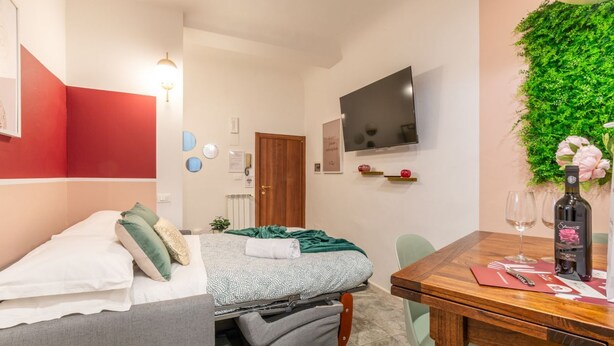 Une pièce de taille modeste comprenant un lit, une table à manger, un téléviseur et un élément de décoration murale de couleur verte.