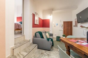 Un espacio habitable pequeño con sofá, una mesa de comedor y una escalera que lleva a otra habitación.