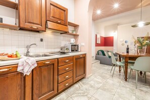 Une cuisine avec des meubles de rangement en bois, un évier et un four à micro-ondes. On y trouve également un coin repas avec une table et des chaises.