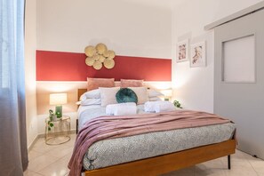 Un dormitorio moderno con una cama de madera, una pared de acento roja y un adorno de pared decorativo.