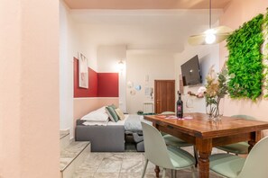 Un espace de vie compact comprenant un coin repas, une petite kitchenette et un téléviseur fixé au mur.