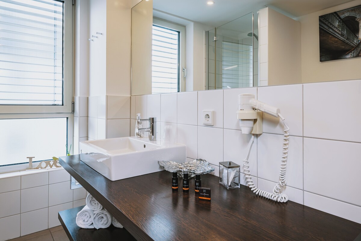 A modern bathroom with a dark wooden countertop, a white sink, and a glass shower enclosure.