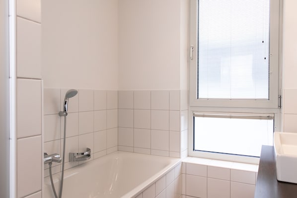 A modern bathroom with a bathtub, a shower, and a window. - Der Gletscherblick by Alpin Rentals - incl Summercard (Kaprun)