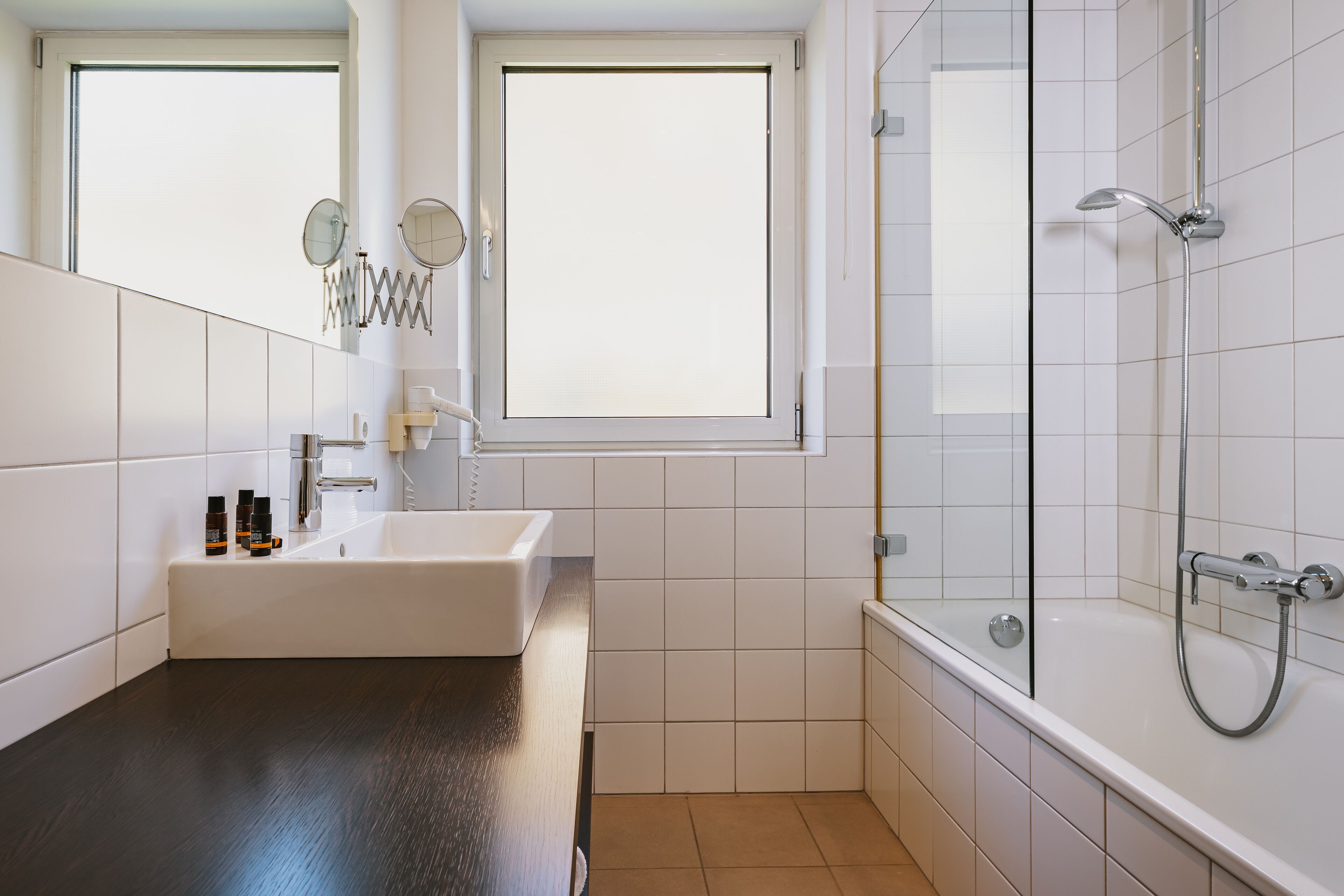 Un bany modern amb un lavabo blanc, un mirall gran i una zona de dutxa amb envàs de vidre.