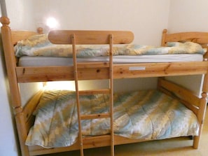 Ein Stockbett mit einer Leiter, einem Holzkopfstück und einer Matratze mit Tarnmuster.