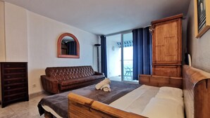 Un dormitorio con una cama grande, un armario de madera, un sofá marrón y un espejo en la pared.