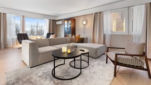 A modern living room with a sectional sofa, a round coffee table, and a wooden chair. - The View (Tromsø)