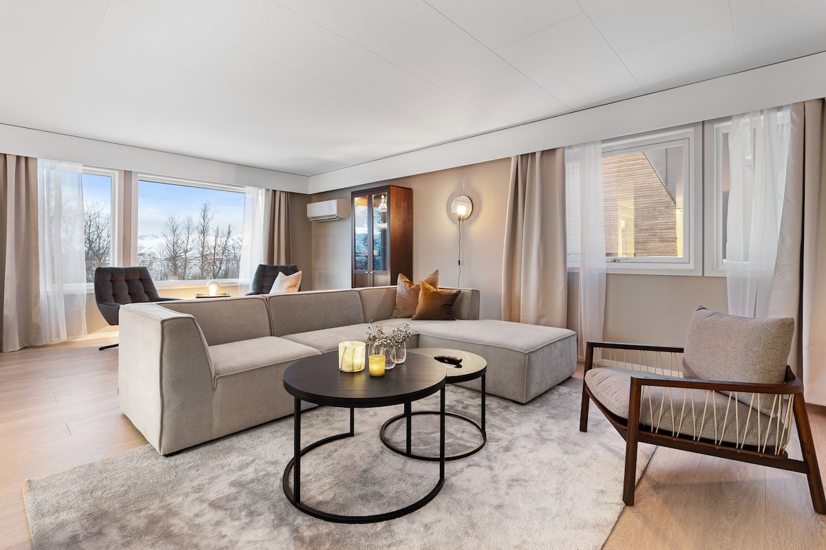 A modern living room with a sectional sofa, a round coffee table, and a wooden chair.