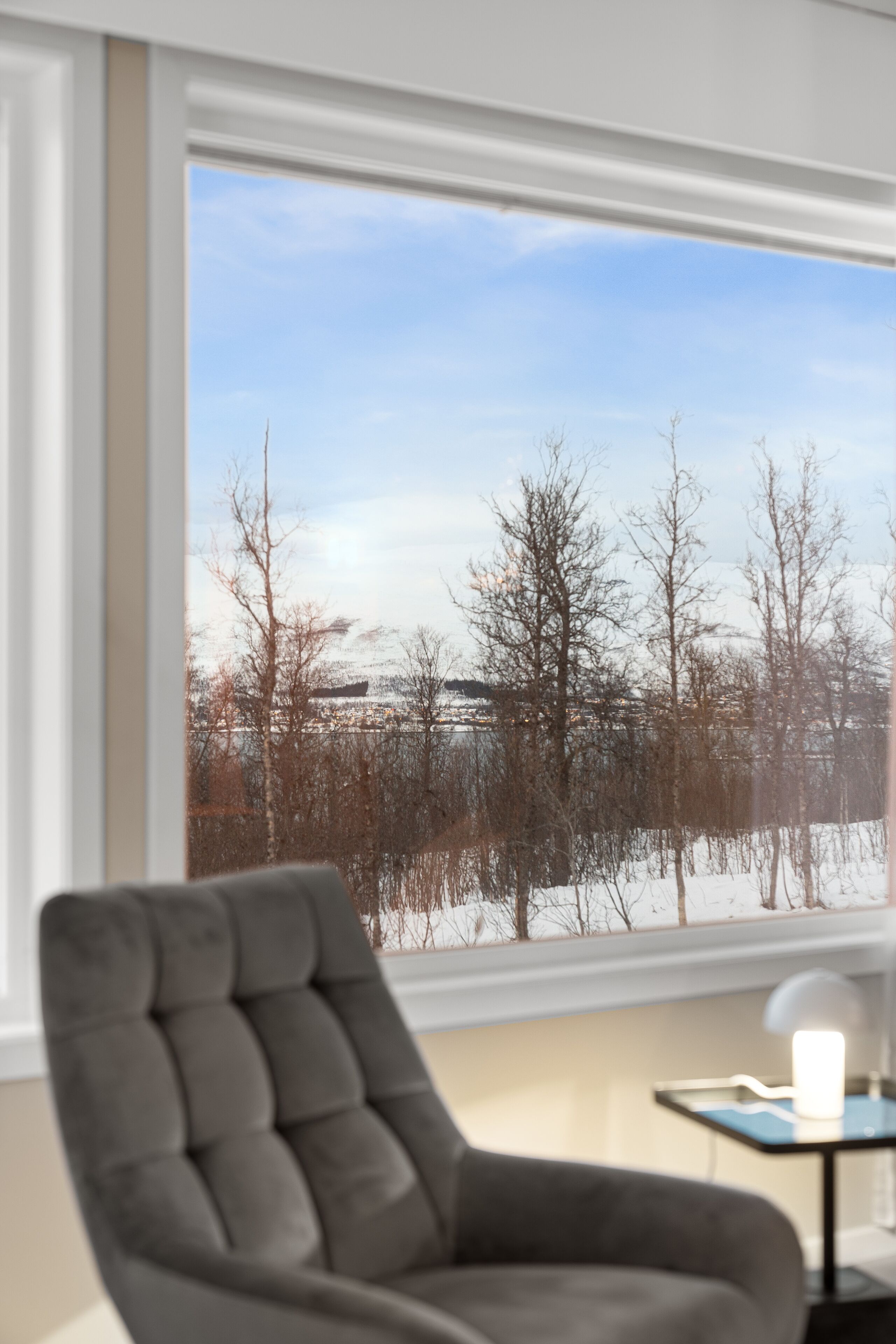 A room with a large window offering a view of a snowy landscape and trees.