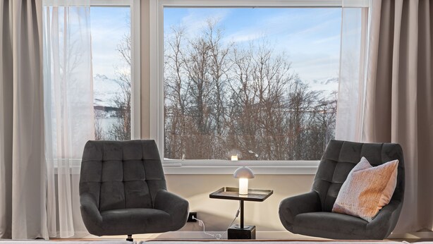 A modern room with two dark armchairs facing a window overlooking a snowy landscape. - The View (Tromsø)