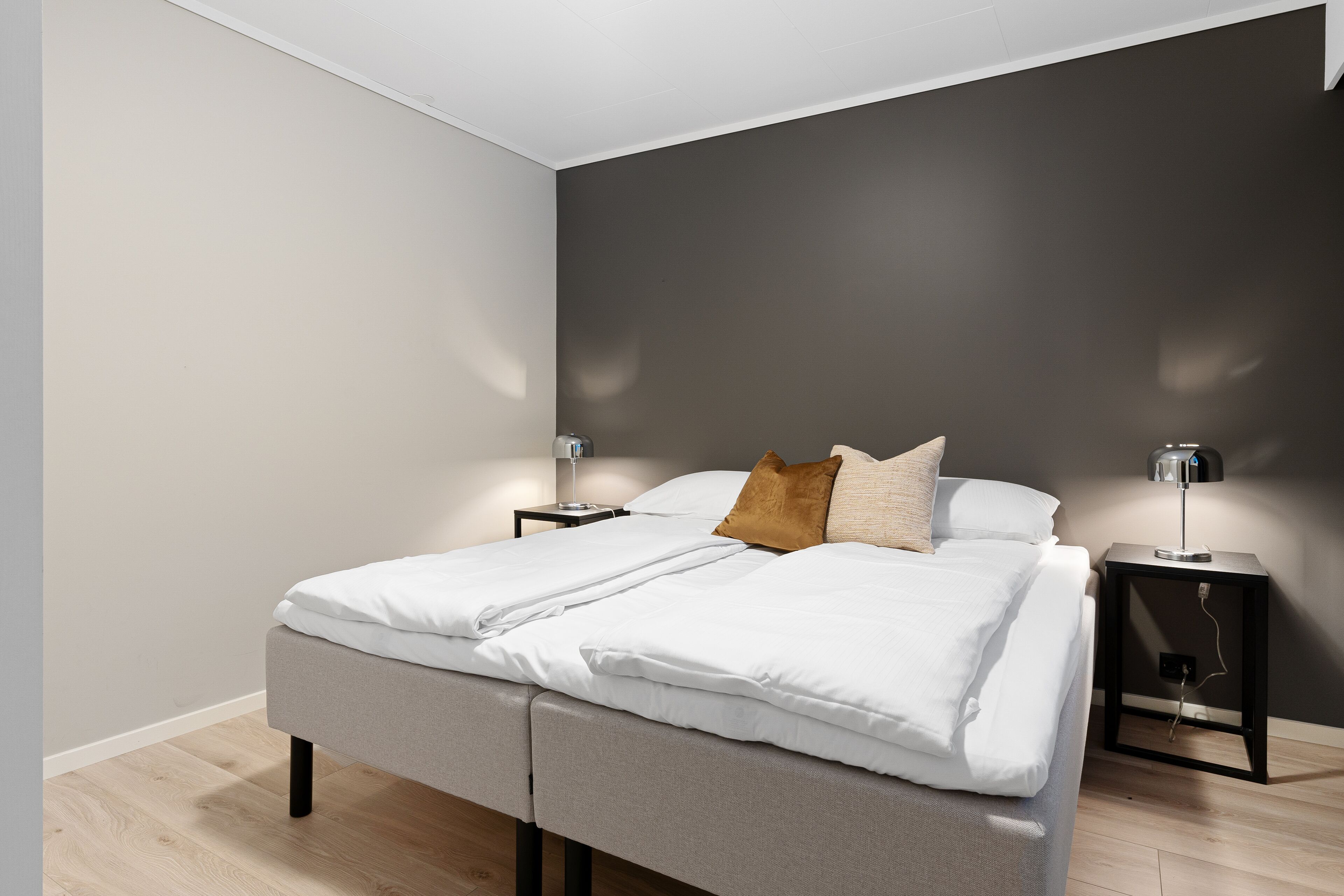 A modern bedroom with a bed, two bedside tables, and a nightstand.