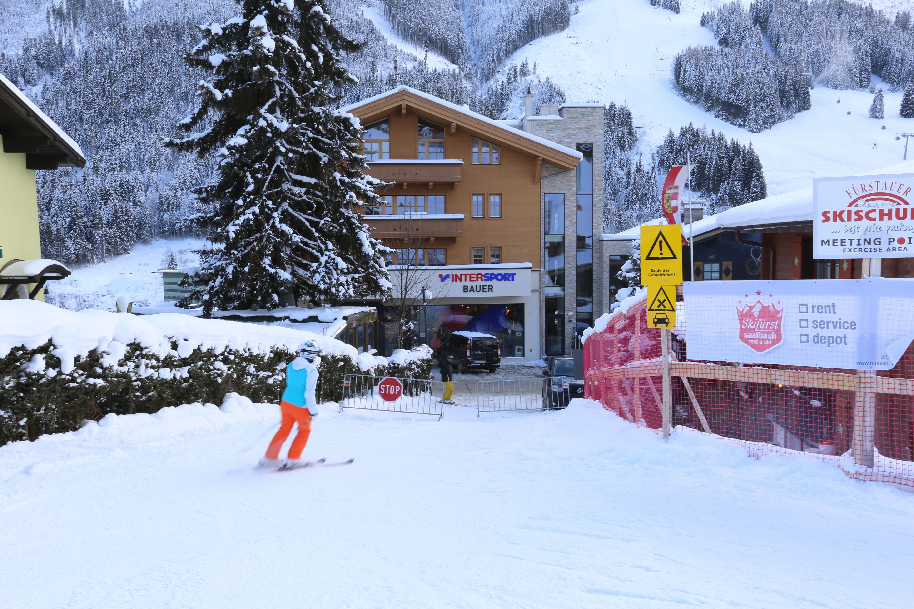 A ski resort with a building labeled "INTERSPORT BAUER" and a sign for "SKISCHUFE FIRSTAUS SAUBACH".
