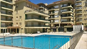 A multi-story residential building with a swimming pool in the foreground. - Charming Apartment with Pool Access, Sea Views and Terrace in Playa de Aro (Platja d'Aro)