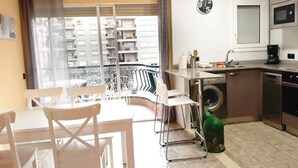 A compact kitchen with a sink, microwave, and a small dining area with chairs. - Charming Apartment with Pool Access, Sea Views and Terrace in Playa de Aro (Platja d'Aro)