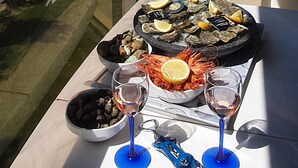 Un balcón con una mesa dispuesta para comer, con vista a la playa y al mar.