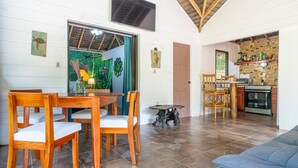 A dining area with wooden chairs and a table, a kitchen with a stove and cabinets, and a living area with a sofa. - Cute. Cozy. Private. Pool. Ojochal. (Ojochal)