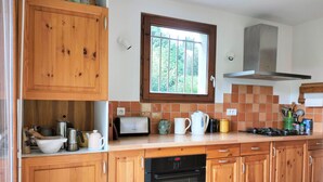 A kitchen with wooden cabinets, a Bosch dishwasher, a toaster, and a window with a view of trees. - Spacious house for 8, 4 bedrooms, mountain view (Corrençon-en-Vercors)