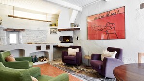 A modern living room with green and purple sofas, a fireplace, and a large abstract painting on the wall.