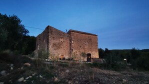 A historic stone building with a rectangular shape, featuring a central entrance and multiple windows.