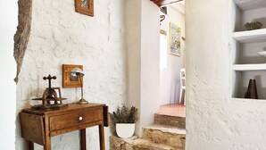 A rustic interior with a wooden desk, a lamp, a potted plant, and a staircase leading to another room.