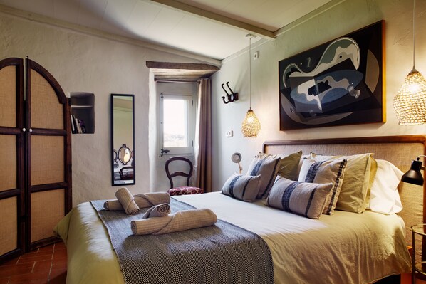 Ein helles Schlafzimmer mit einem großen Bett, einem Holzschrank, einem Spiegel und einem Bild an der Wand.