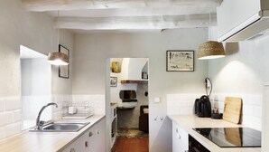 A narrow kitchen with white cabinets, a black stove, and a tiled backsplash.