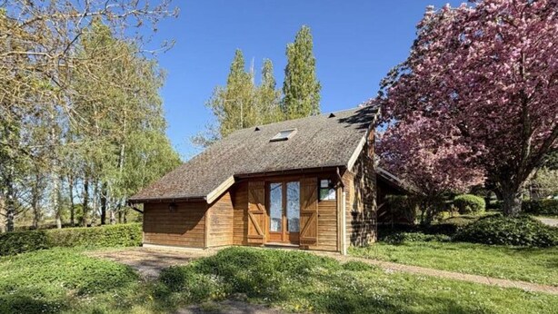 Una cabaña de madera con techo inclinado, una puerta principal y un porche pequeño.