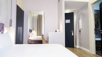 A modern hotel room with a large bed, a desk, and a bathroom visible through an open door.
