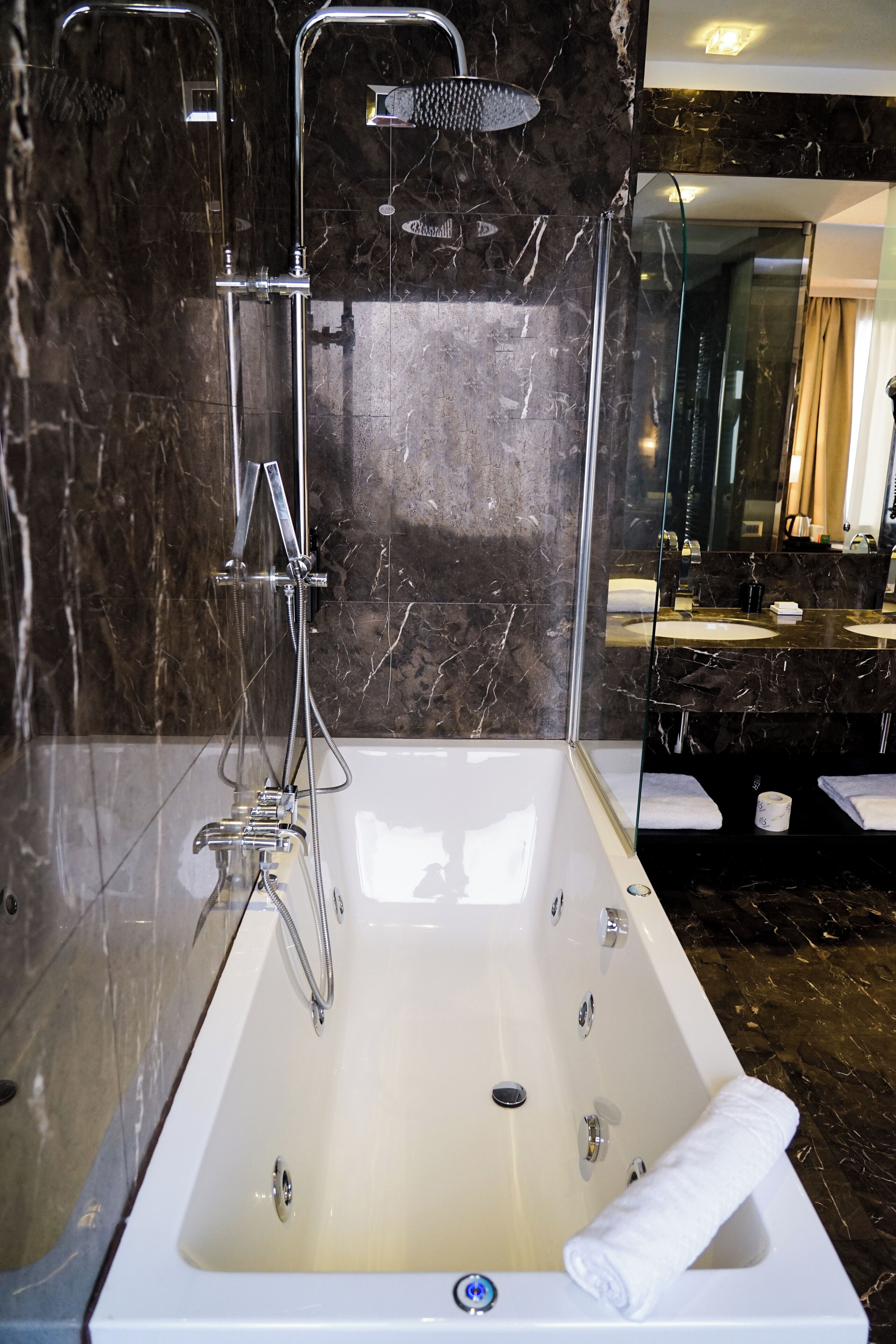 A modern bathroom with a large bathtub, a glass-enclosed shower, and a vanity with two sinks.