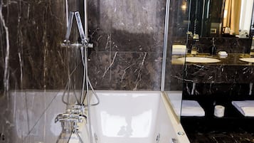 A modern bathroom with a large bathtub, a glass-enclosed shower, and a vanity with two sinks.