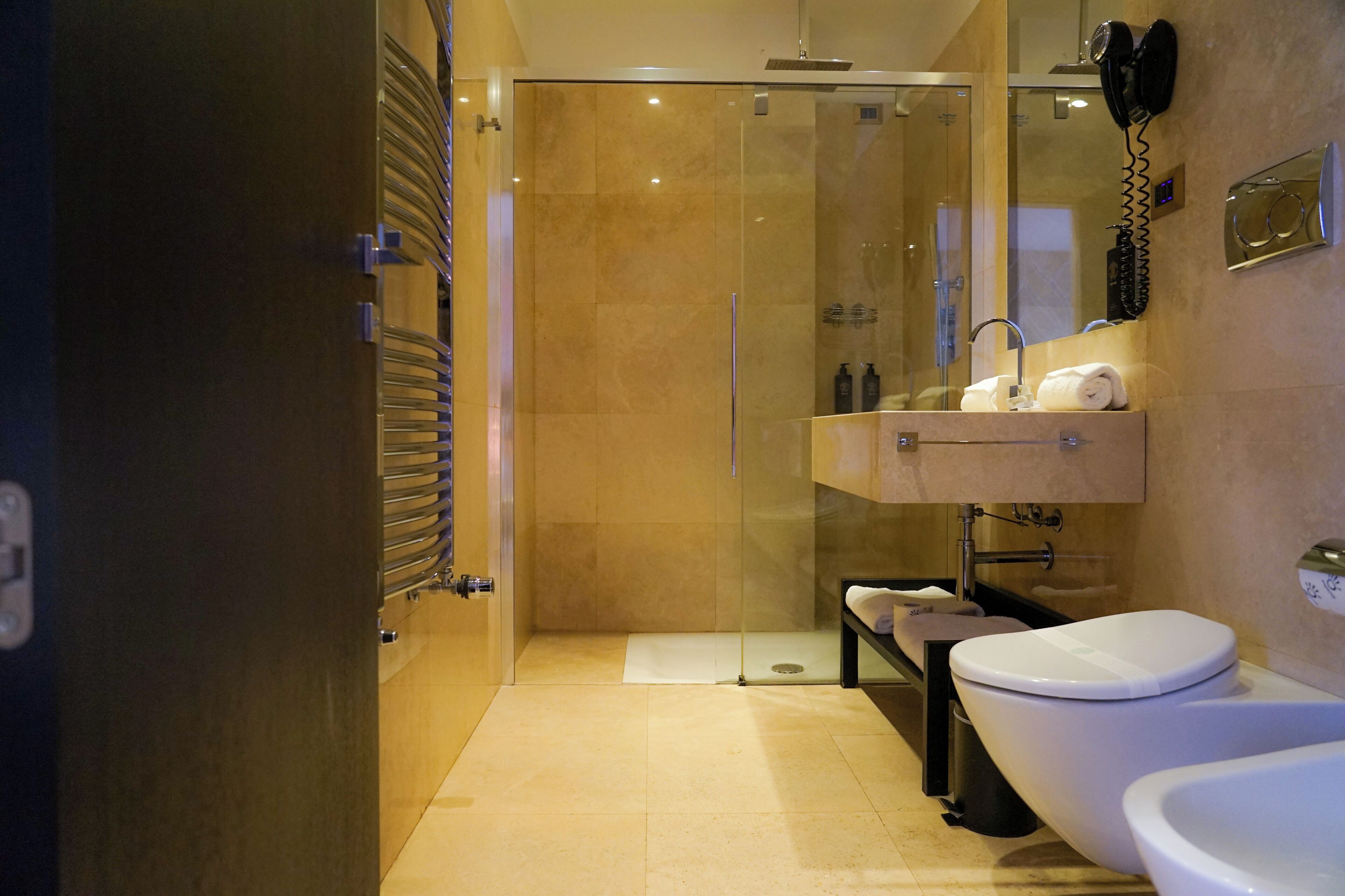 Un bagno moderno con cabina doccia in vetro, un mobile lavabo con specchio e il water.